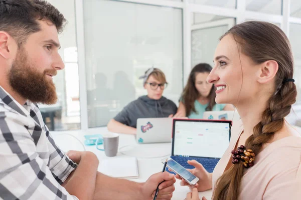 Creative female freelancer smiling to co-worker