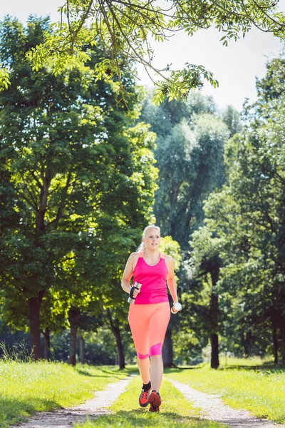 Женщина бежит по тропинке на лугу с гантелями — стоковое фото