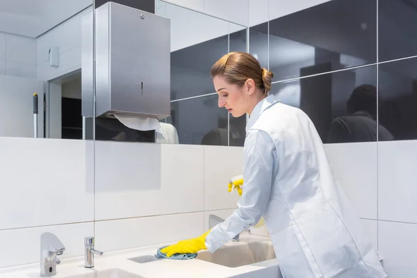 Janitor cleaning sink in public washroom — Stock Photo, Image