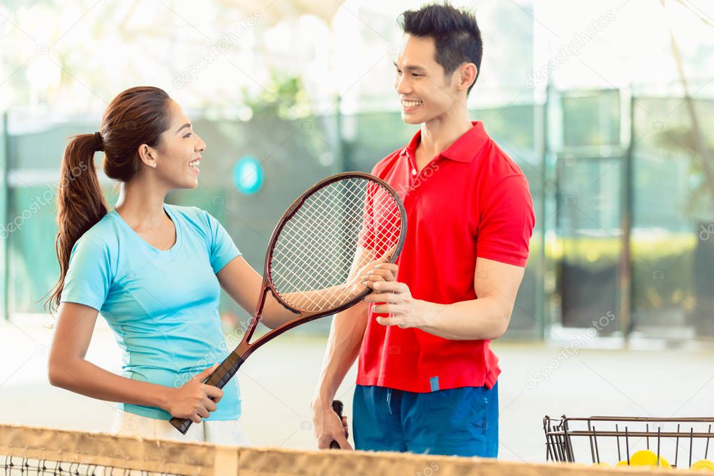 Tennis instructor teaching a beginner player the correct grip