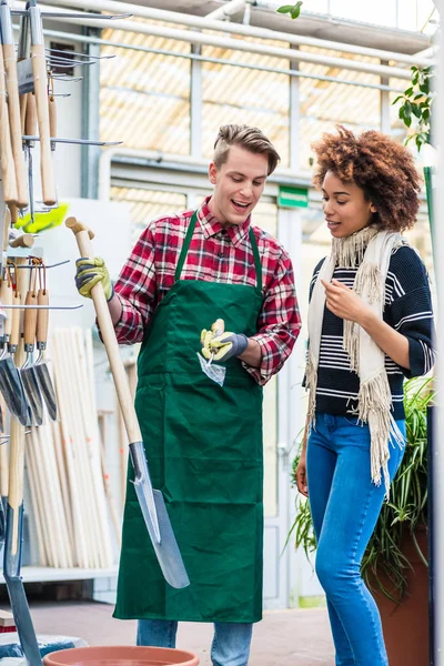 Handsome worker helping a customer with choosing a gardening tool — Stock Photo, Image