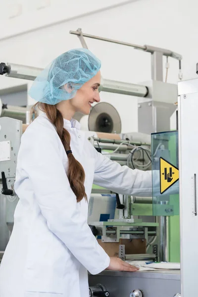 Vrouw productie ingenieur aanpassen van de instellingen van een industriële machine — Stockfoto