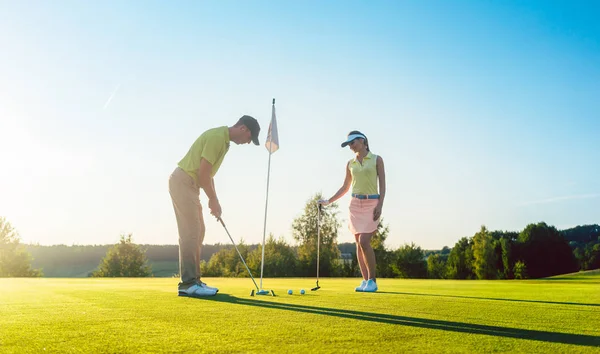 Man ready to hit the golf ball while exercising with his game partner — Stock Photo, Image