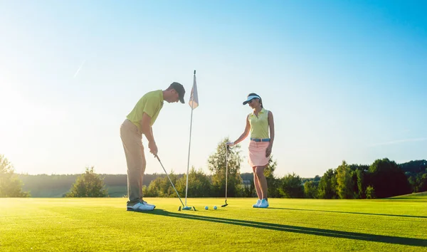 Muž připraven zasáhnout golfový míček při cvičení s jeho herní partner — Stock fotografie