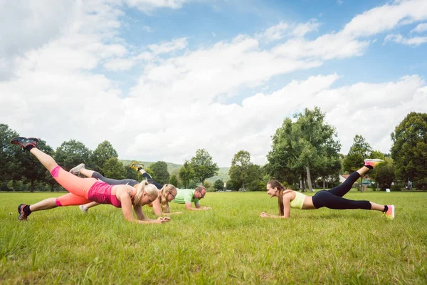 Familie plankt draußen auf Wiese mit Fitnesslehrer — Stockfoto