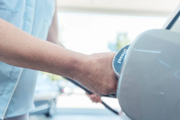 Close-up van de hand van een senior vrouw opvullen van de gastank van haar auto — Stockfoto