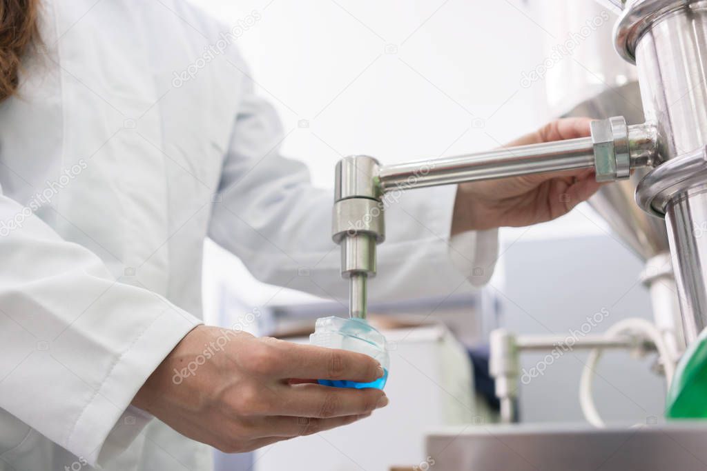 Technician filling container with liquid for laboratory tests