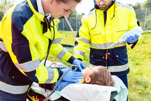 Paramedics measuring blood pressure of injured boy — Stock Photo, Image