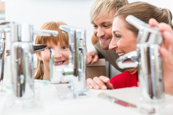 Ritratto di una famiglia felice alla ricerca di un nuovo rubinetto del lavandino del bagno — Foto Stock