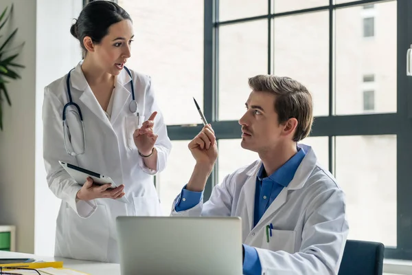 Jeune femme médecin demandant conseil à son collègue expérimenté — Photo