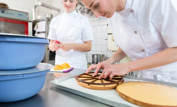 フルーツ ケーキにリンゴのスライスを置くことで働くパティシエ女性 — ストック写真