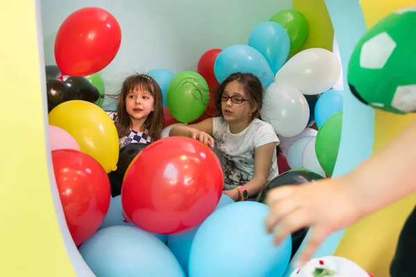 Duas meninas bonitos falando enquanto joga com balões multicoloridos — Fotografia de Stock