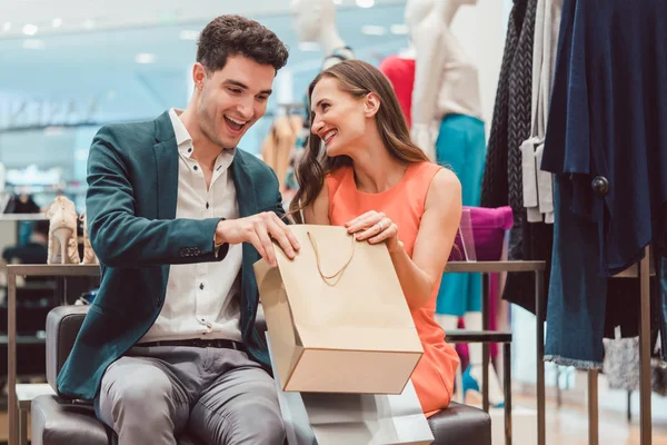 Mulher mostrando a seu homem o que ela comprou na loja de moda — Fotografia de Stock