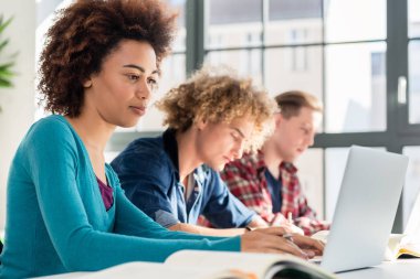 Online bilgi için bir dizüstü bilgisayar kullanırken gülümseyen öğrenci
