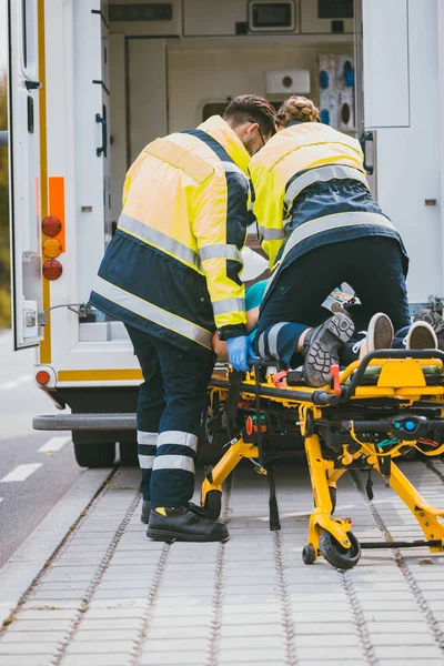 Paramédico en camilla luchando por la vida de la mujer lesionada —  Fotos de Stock