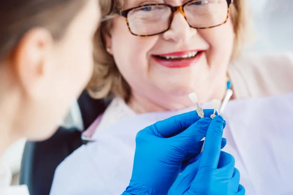 Zahnarzt zeigt älteren Patienten Proben von Zahnfarben — Stockfoto