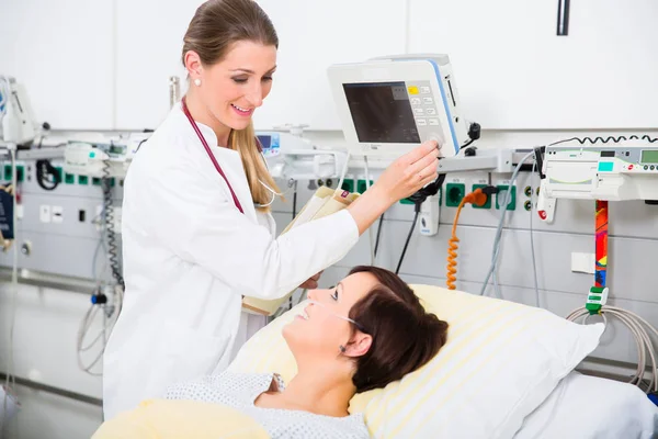 Médico em cuidados médicos intensivos verificando resultados de paciente mulher — Fotografia de Stock