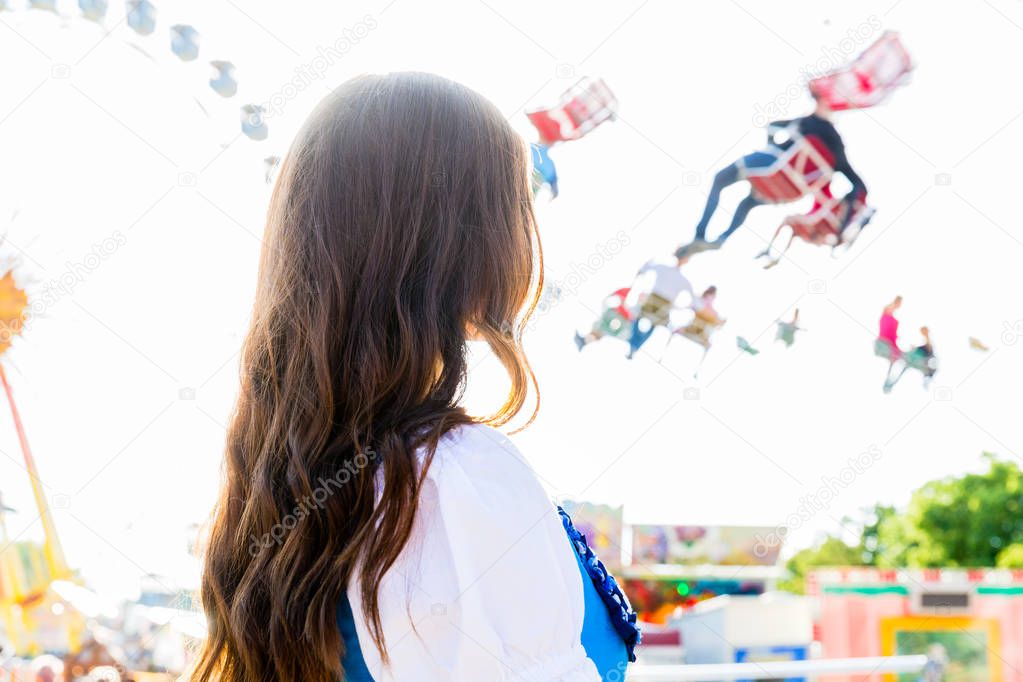 woman wearing dirndl standing in front of ferris wheel
