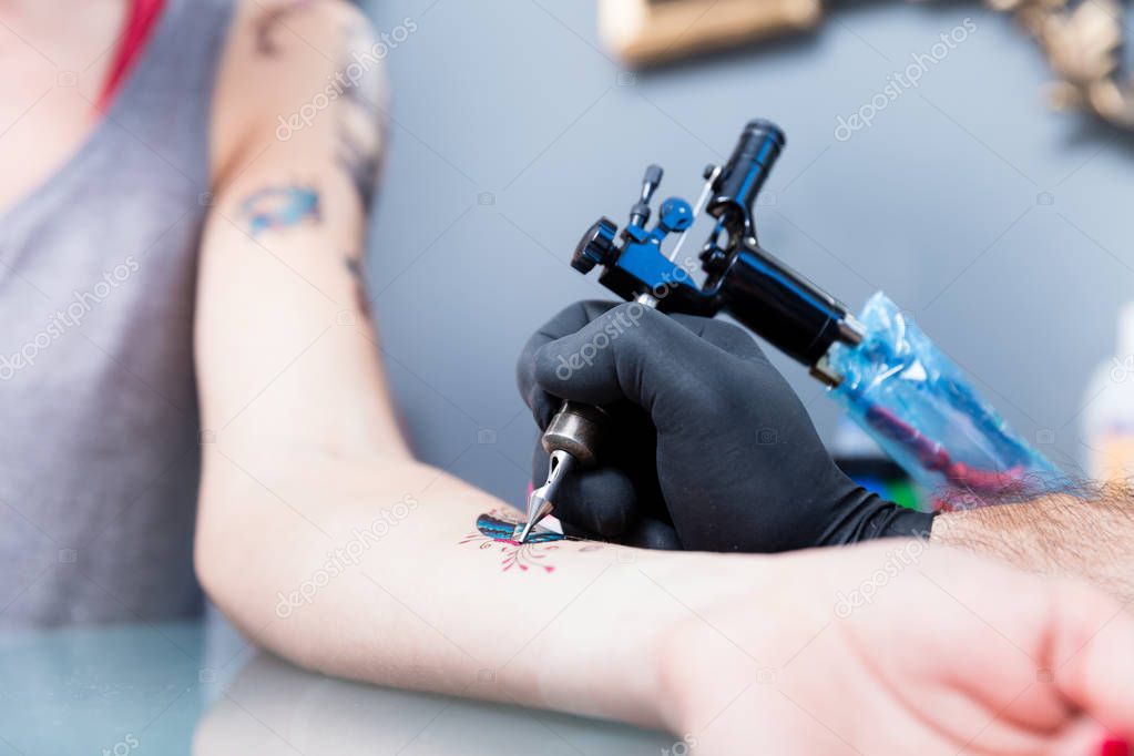 Close-up of the hand of a tattoo artist shading a colorful butterfly