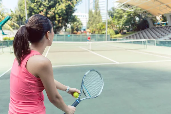 Vista posteriore di una giovane donna in forma che gioca a tennis su un campo professionale — Foto Stock