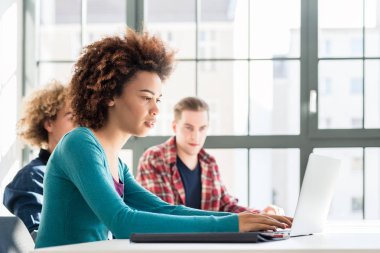 Online bilgi için bir dizüstü bilgisayar kullanırken gülümseyen öğrenci