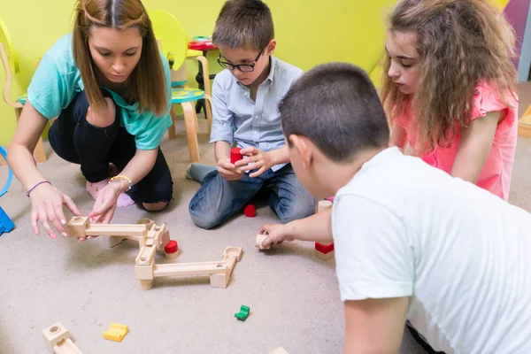 Speciale kleuterjuf helpen kinderen met bouw — Stockfoto