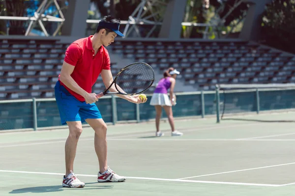 Jogador de tênis asiático pronto para servir no início de um jogo de duplas — Fotografia de Stock