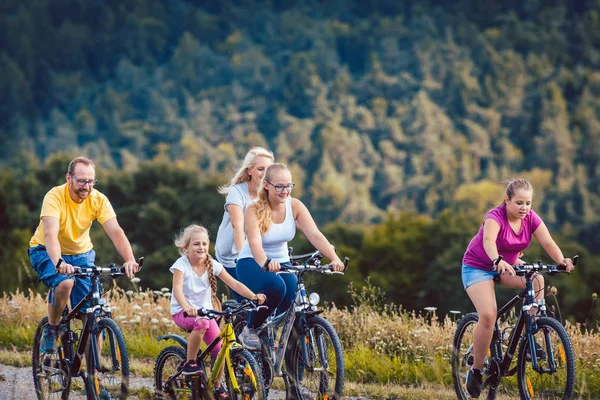 Familia montando sus bicicletas en la tarde en el campo — Foto de Stock