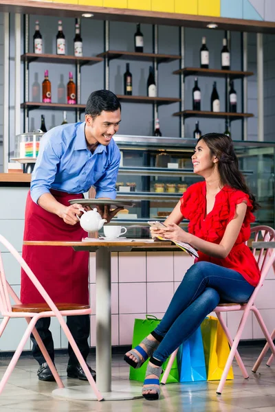 Camarero guapo sirviendo café en la mesa de dos hermosas mujeres — Foto de Stock