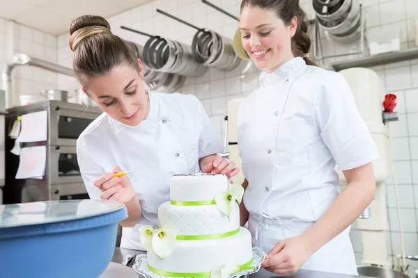 Dos panaderos de pastelería decorando pastel grande — Foto de Stock