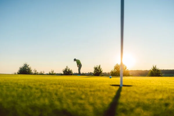 Silueta de un jugador masculino golpeando un tiro largo en el campo de golf — Foto de Stock