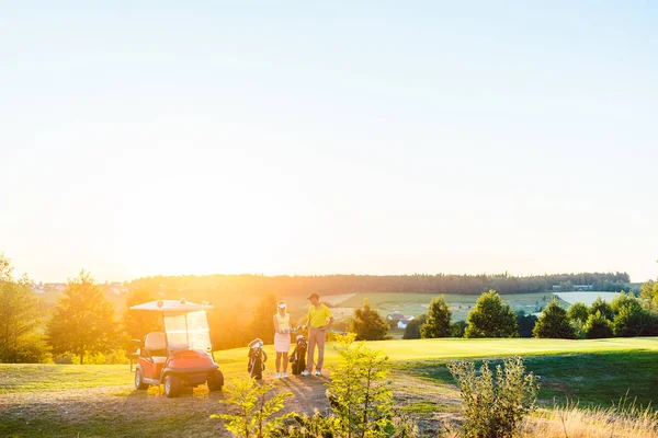 Täyspitkä nainen ja hänen kumppaninsa tai ohjaaja, jolla on erilaisia golfmailoja — kuvapankkivalokuva