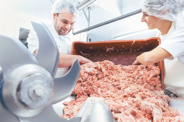 Team of butchers taking minded meat out of grinder — Stock Photo, Image