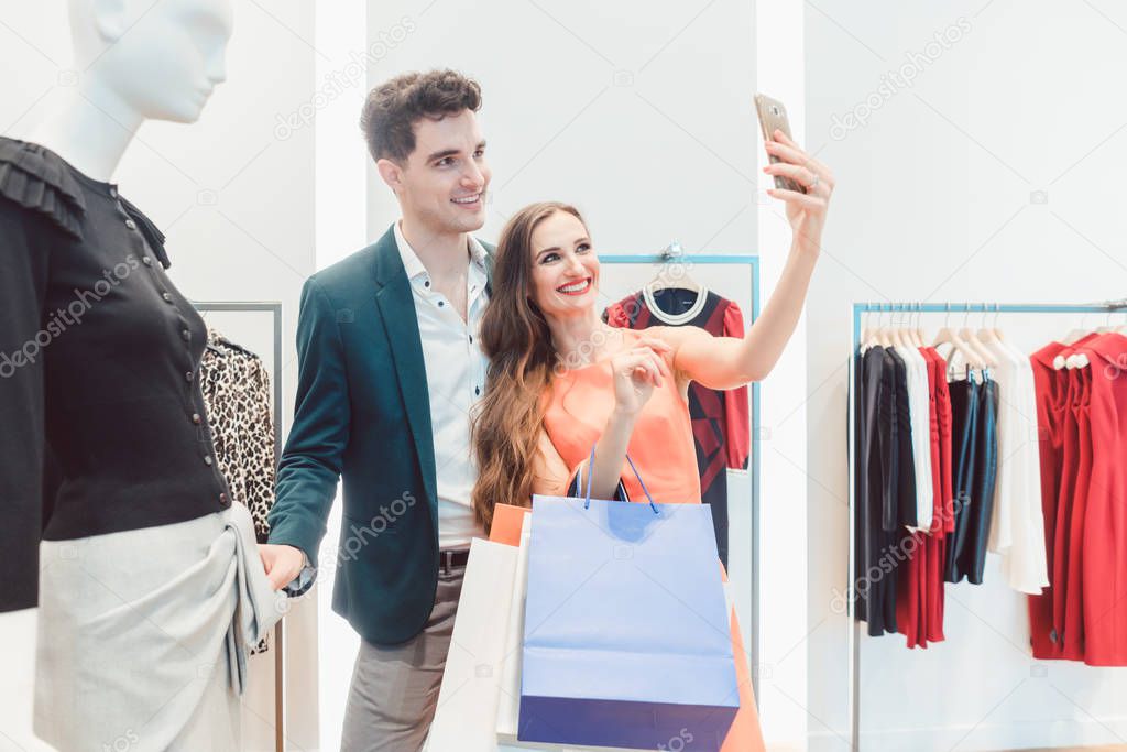 Couple doing selfie phone photo with their catch in fashion store