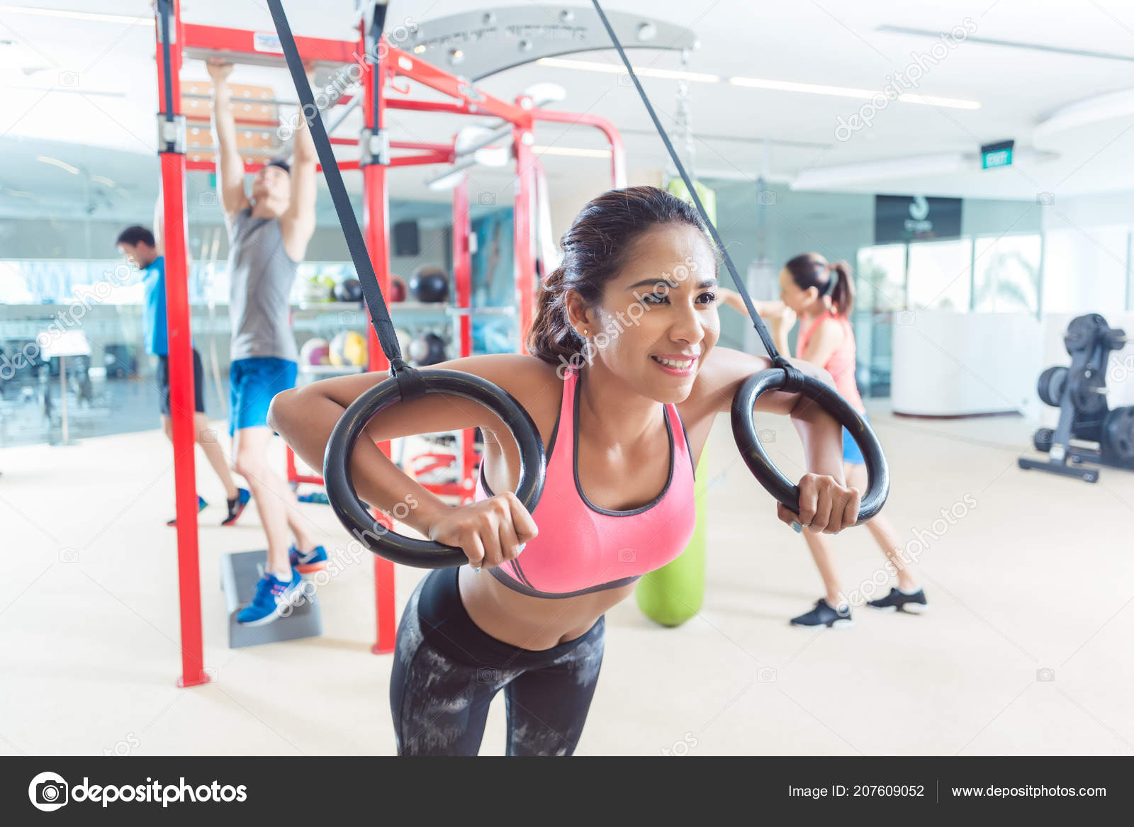 Fit Young Woman Exercising With Gymnastic Rings In A Trendy Fit Young Woman Exercising With Gymnastic Rings In A Trendy
