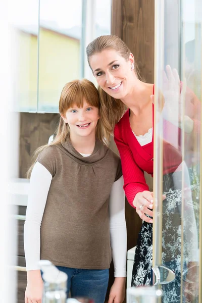 Donna allegra con sua figlia guardando una cabina doccia — Foto Stock