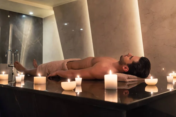 Uomo rilassante sul lettino da massaggio al centro spa e benessere asiatico — Foto Stock