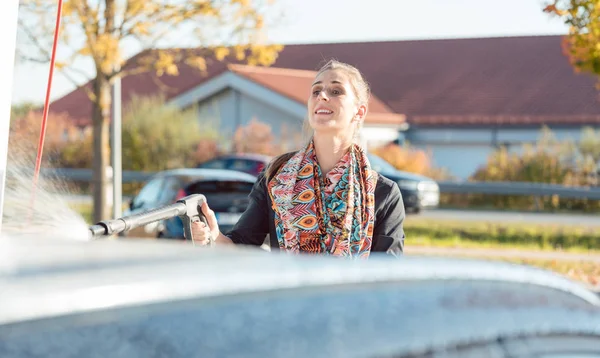 Mulher usando bocal de alta pressão para limpar seu carro — Fotografia de Stock