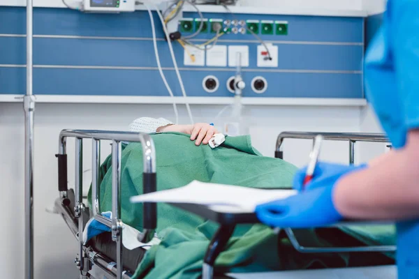 Zdravotní sestra odepsat údaje o pacienta v pooperačním pokoji moderní nemocnice — Stock fotografie