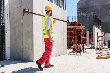 Mavi yakalı işçi ağır metal çubuk çalışmaları sırasında taşıma