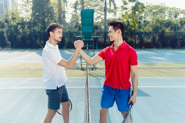 Dois jogadores profissionais de tênis apertando as mãos como um gesto de fair play — Fotografia de Stock