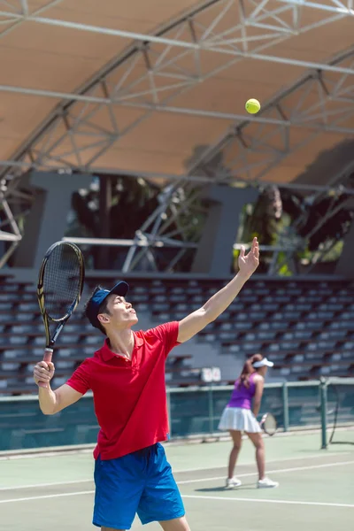 Giocatore di tennis asiatico pronto a servire all'inizio di una partita di doppio — Foto Stock