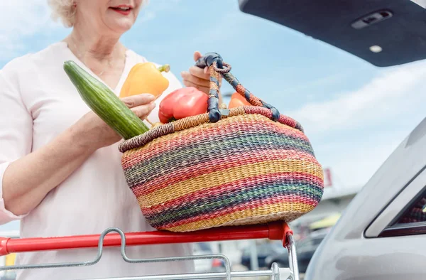 Wanita senior yang ceria memegang keranjang penuh sayuran segar — Stok Foto
