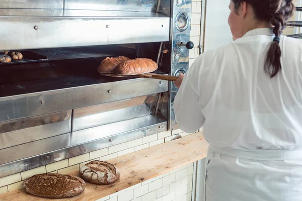 Bäcker holt frisches Brot mit Schaufel aus dem Ofen — Stockfoto