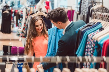 Kadın ve erkek moda mağaza elbiseyle rengini tartışıyor