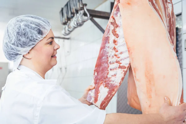 Butcher woman cutting meat for further use — Stock Photo, Image