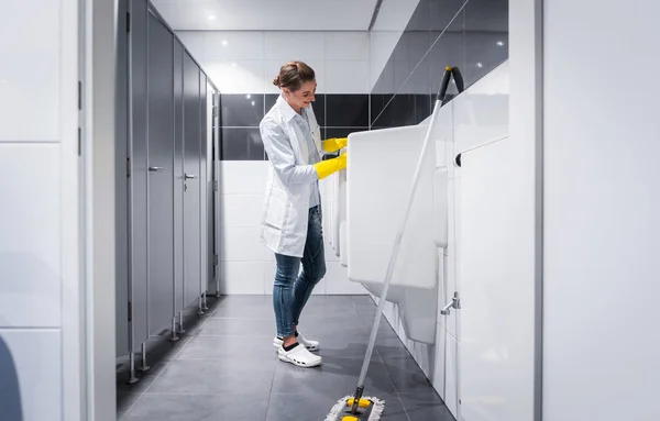 Hausmeisterin reinigt Pissoirs in öffentlicher Toilette — Stockfoto