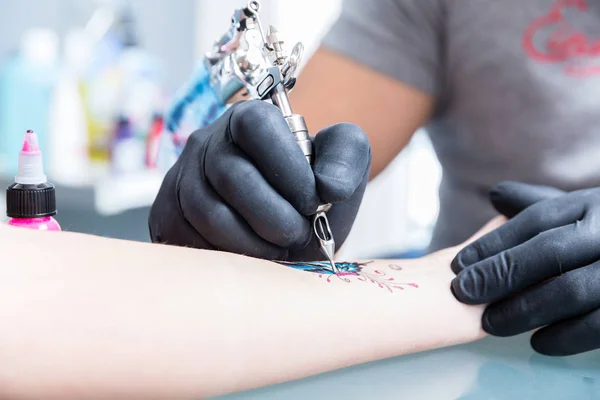 Közeli kép: a kezében egy képzett tetováló művész fekete kesztyűben — Stock Fotó