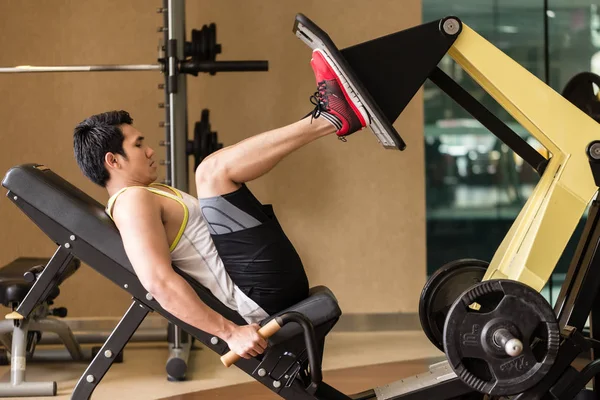 Hombre joven haciendo ejercicio en la prensa de la pierna durante el entrenamiento de la parte inferior del cuerpo — Foto de Stock