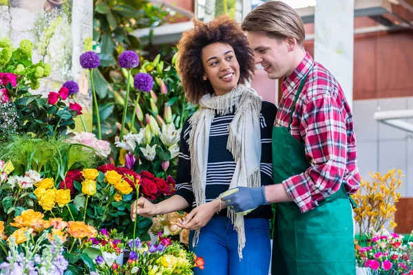 Beautiful woman buying freesias at the advice of a helpful vendor — Stock Photo, Image